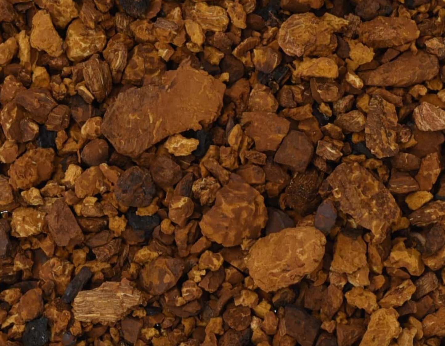 Close-up texture of dried chaga mushroom, showing small dark brown pieces used for teas and herbal remedies.