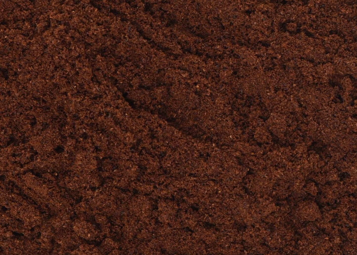 Close-up texture of dried clove bud powder, showing dark brown powder used for teas and herbal remedies.
