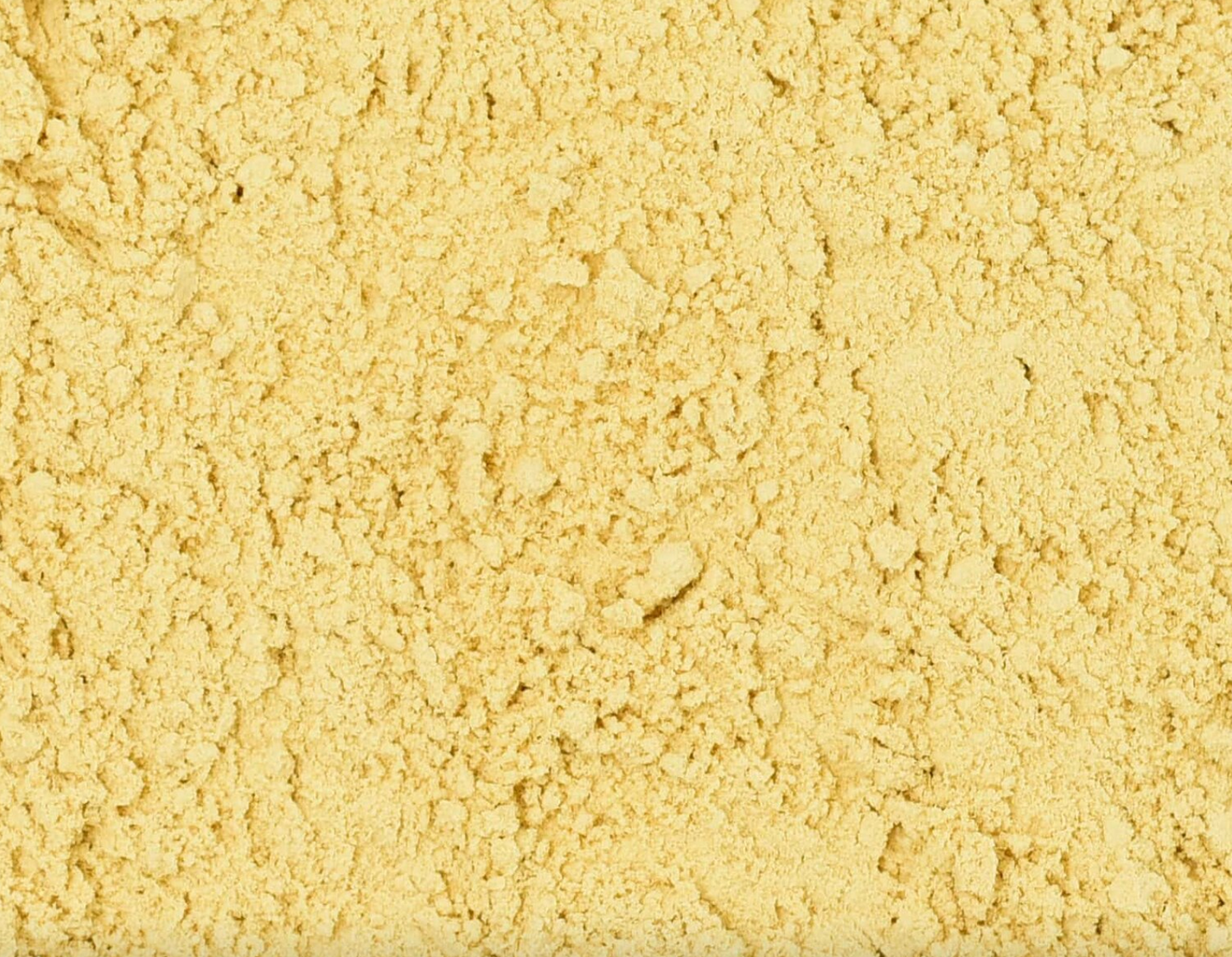 Close-up of dried ginger root powder, showing finely ground beige powder used for teas and herbal remedies.