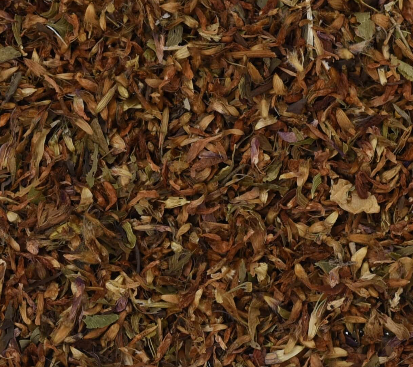 Close-up of dried red clover flowers, showing chopped flower pieces used for teas and herbal remedies.