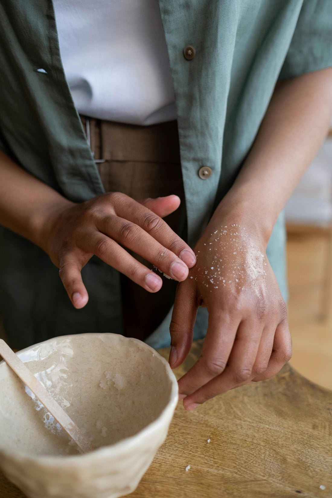 A person rubs body scrub on the top of their hand.